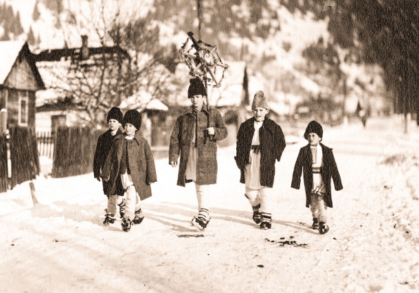5 copii care merg la colindat, cel din mijloc ținând steaua